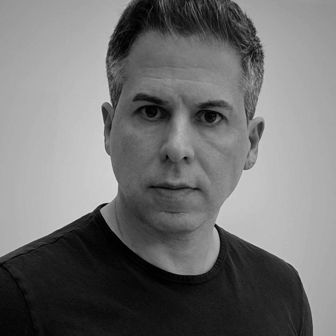 Man in black T-shirt looking serious, professional portrait.